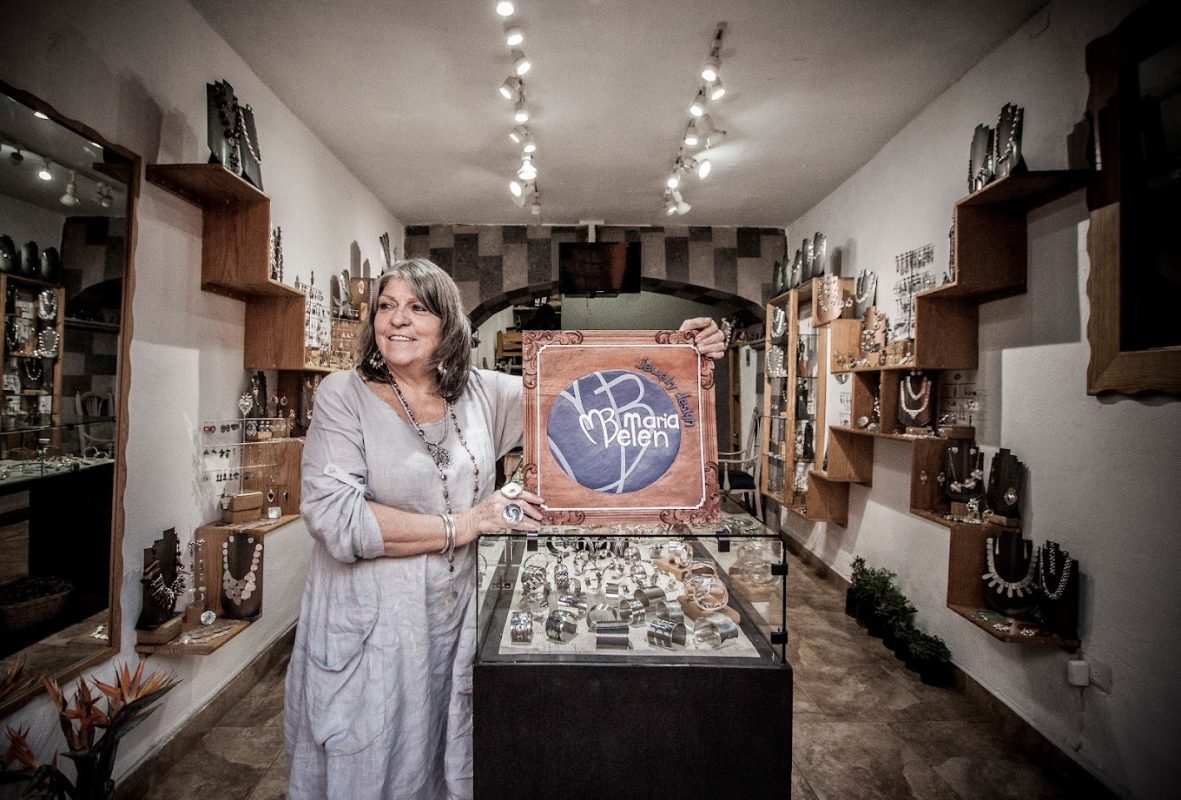 María Belén Nilson displaying a sign with the logo of the store located in San Miguel de Allende